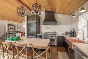Una cocina moderna con una isla central, electrodomésticos de acero inoxidable y vigas de madera en el techo.