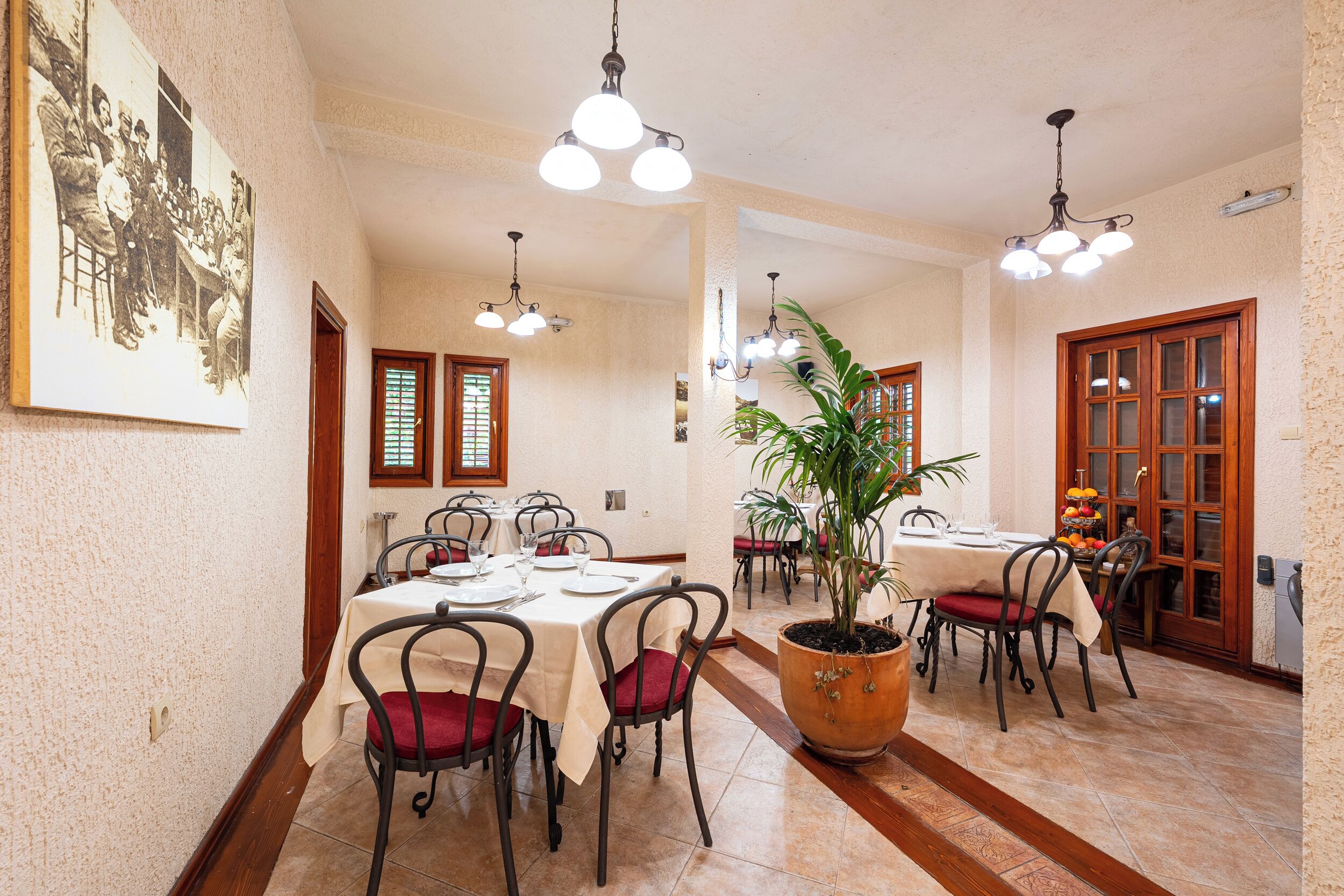 A dining area with multiple tables, chairs, and hanging light fixtures.
