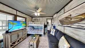 Ein Wohnzimmer mit Fernseher, Etagenbetten, einer Couch und einem Deckenventilator.
