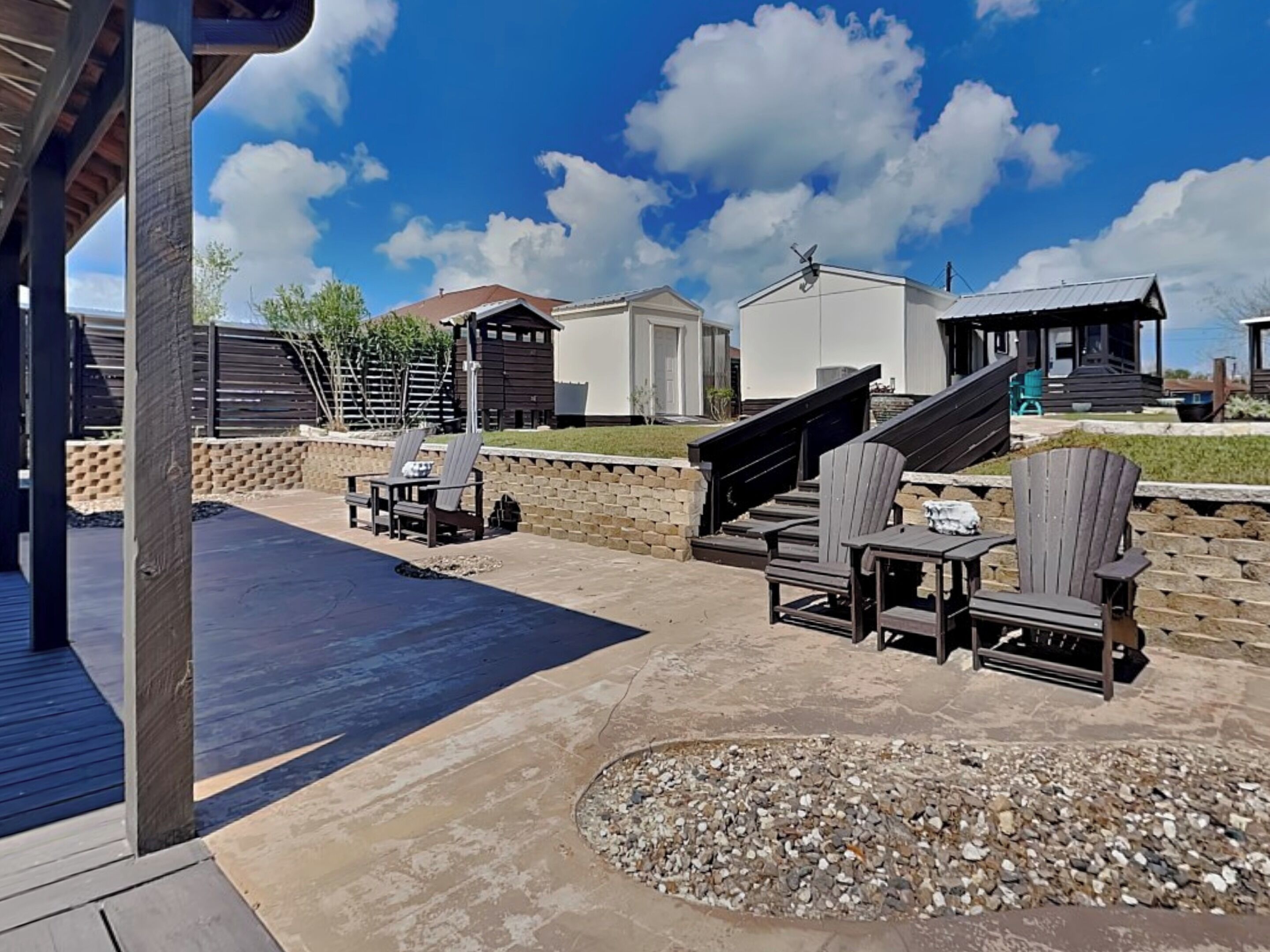 An outdoor patio area with a pool, lounge chairs, and a stone fire pit.