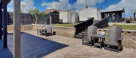 An outdoor patio area with a pool, lounge chairs, and a stone fire pit.