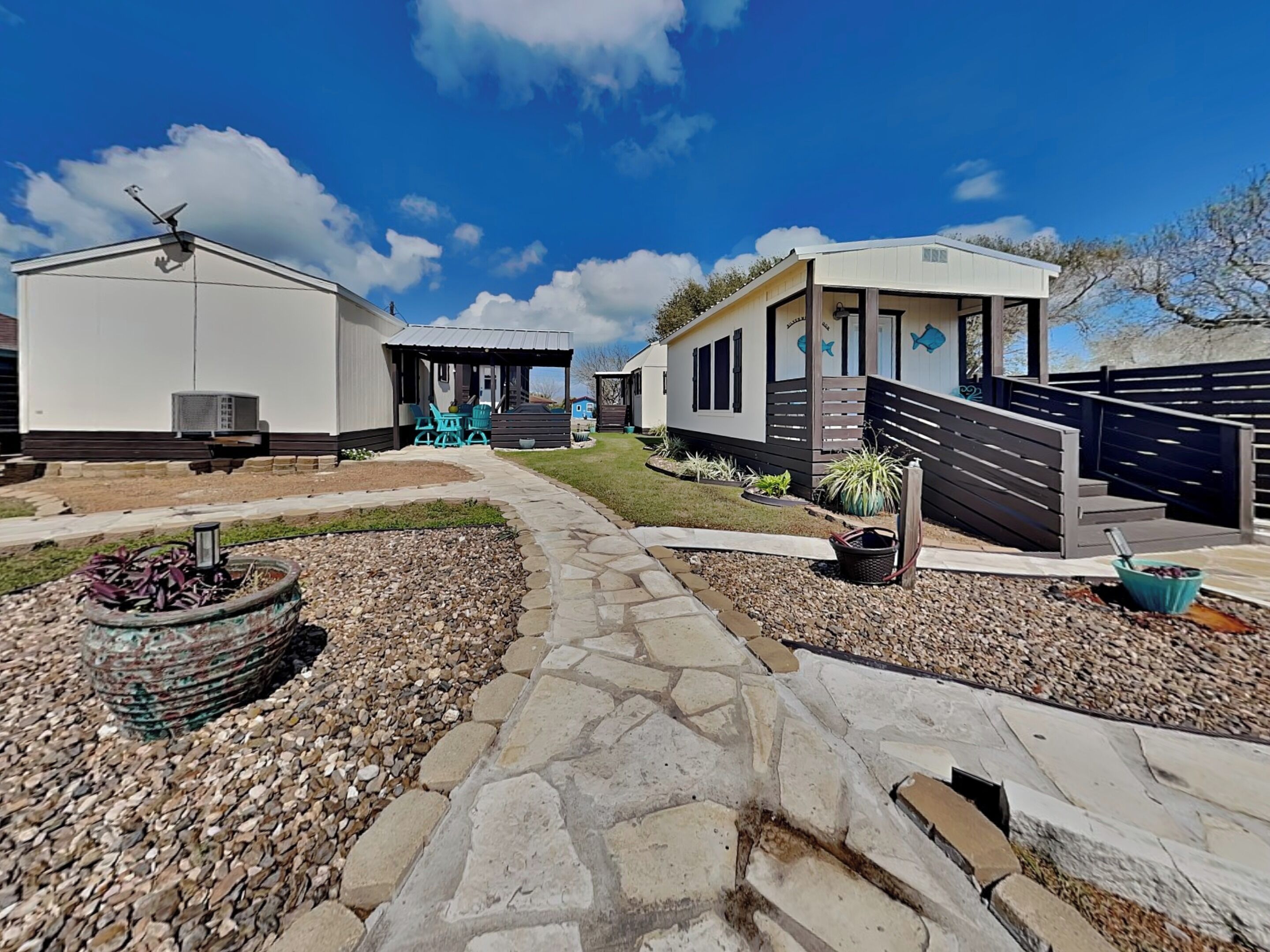 A caravan park with multiple caravans, a stone pathway, and a small fire pit.