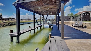 Eine überdachte Holzterrasse über Wasser mit Blick auf ein Gebäude im Hintergrund.