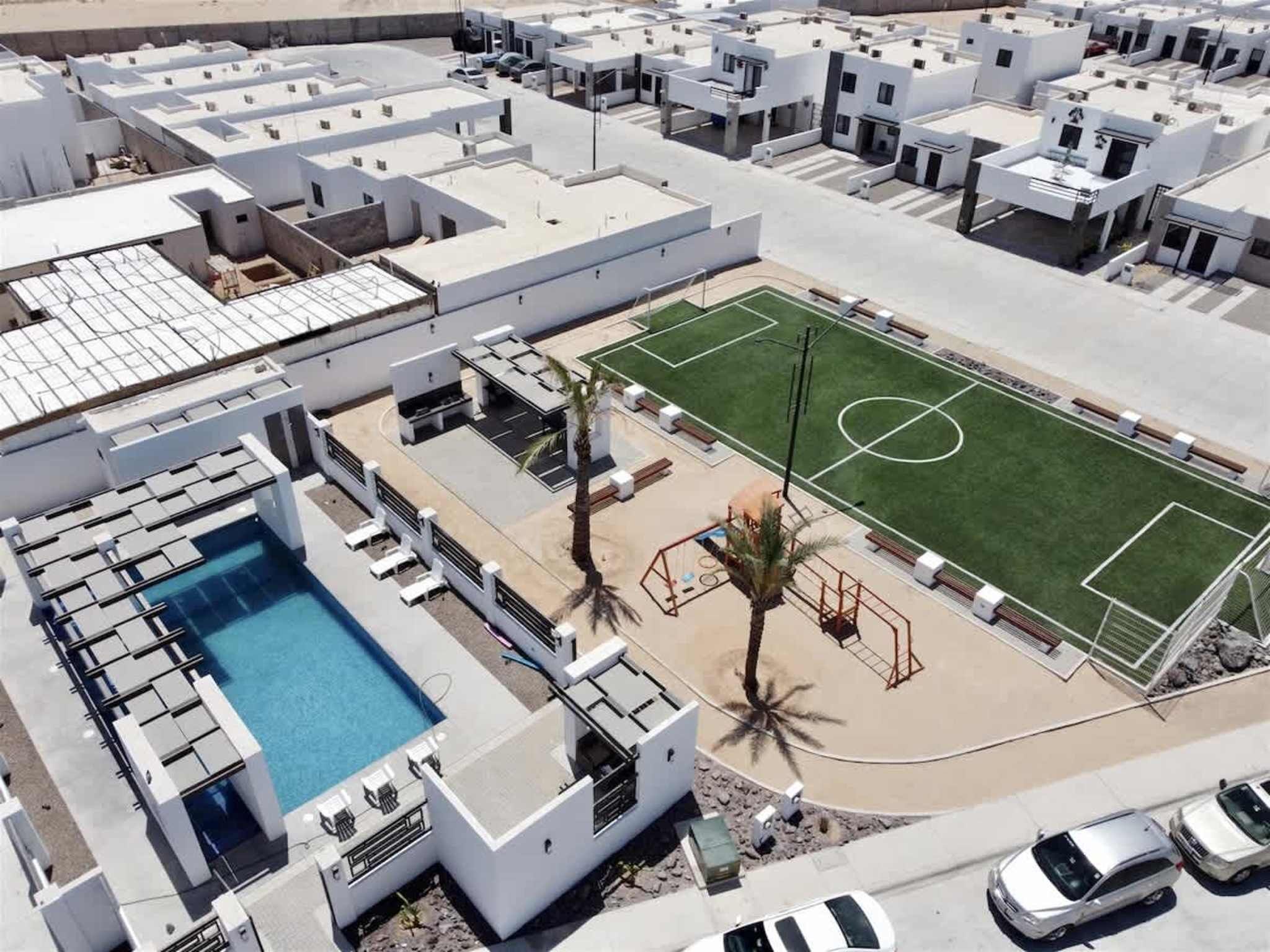 A rooftop with a swimming pool, a tennis court, and several buildings.