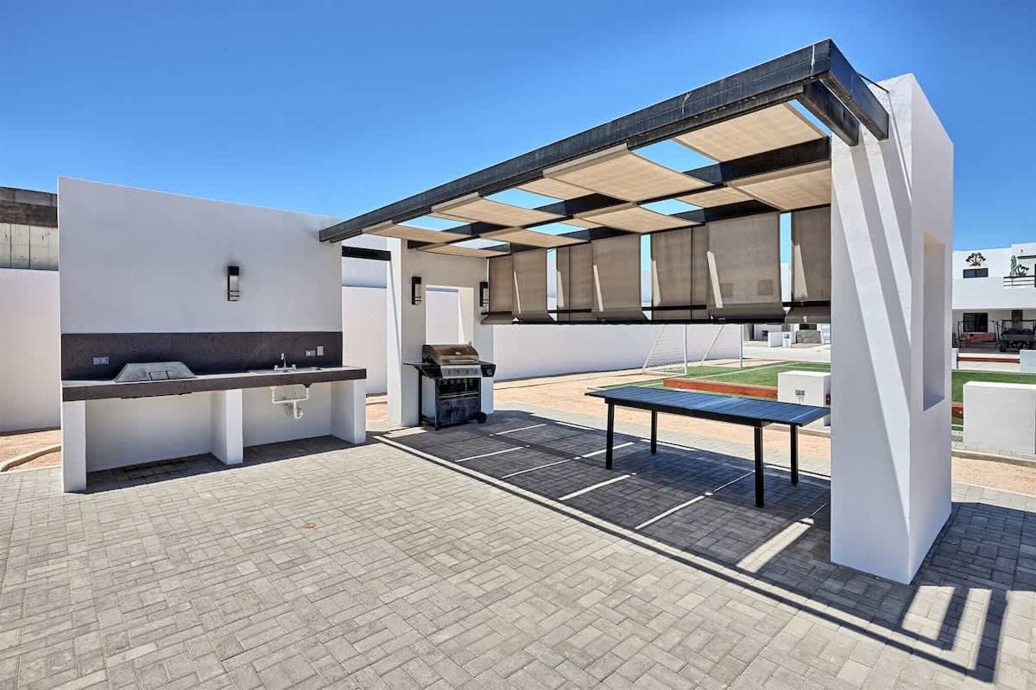 An outdoor patio area with a grill, a sink, and a table.