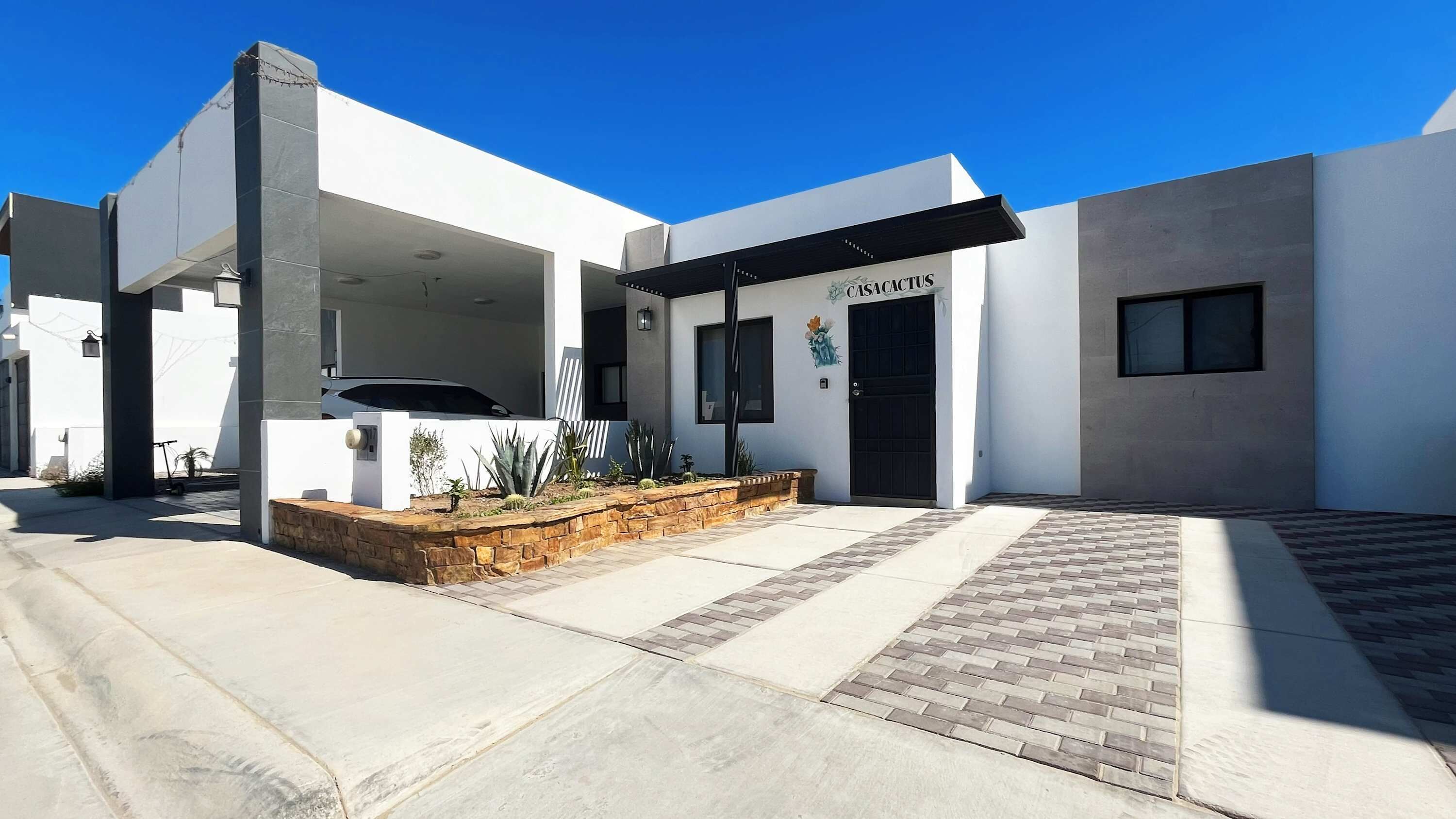 Un bâtiment moderne doté d’un espace extérieur couvert, d’un garage et d’un jardin bien entretenu.
