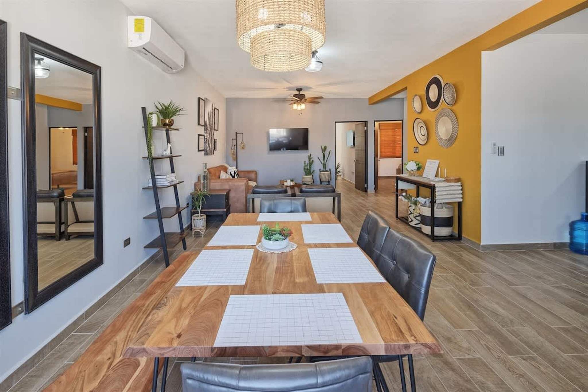 Ein Essbereich mit Holztisch, Stühlen, Deckenventilator und Wandfernseher.