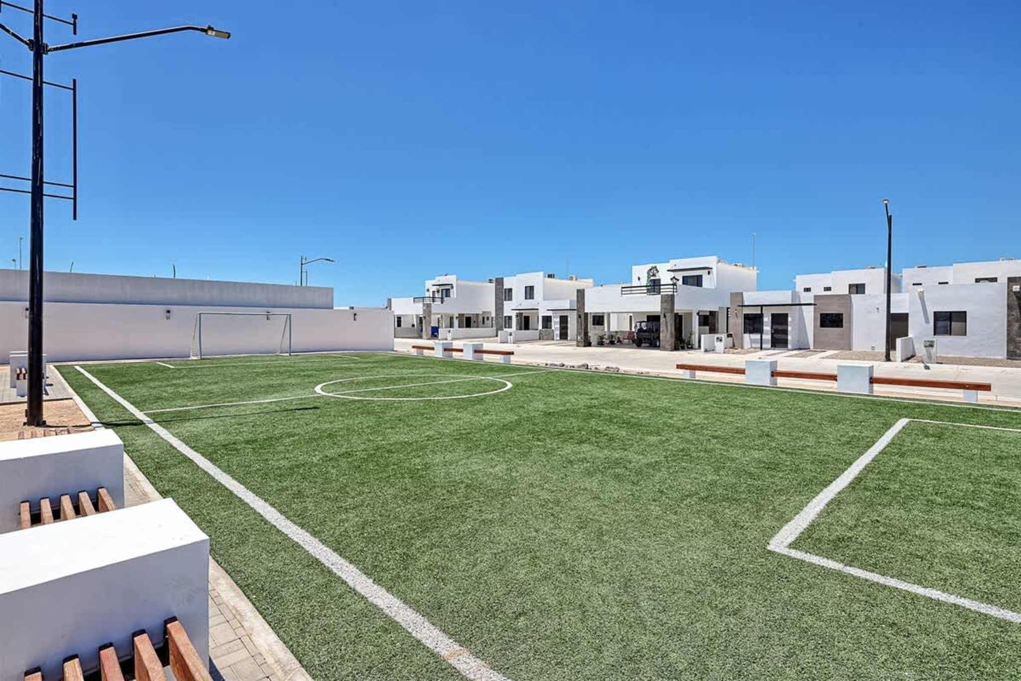 Ein Sportplatz mit weißen Gebäuden im Hintergrund.