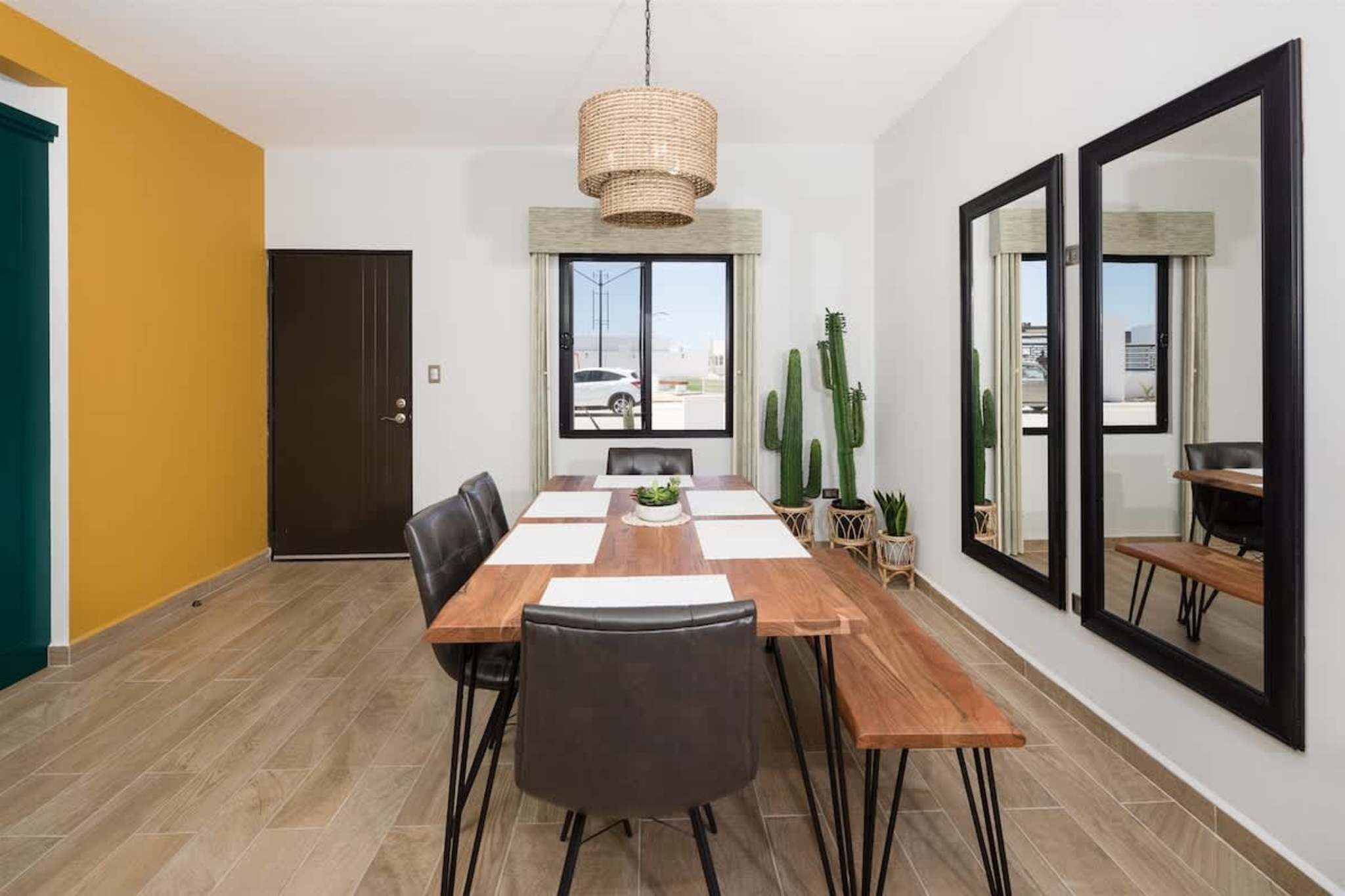 A dining area with a wooden table, chairs, and a hanging light fixture.