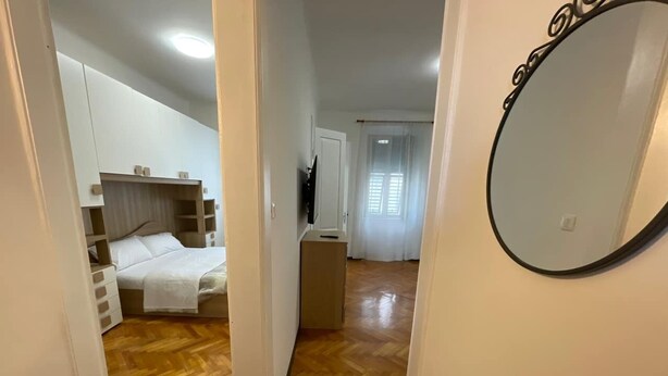 Una habitació amb llit, una petita taula de treball i un mirall a la paret.