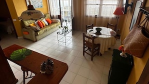 A living room with a sofa, coffee table, and dining area with chairs and a table. - CHL Mayoysa Vista mar en Bre a Baja La Palma (Brena Baja)