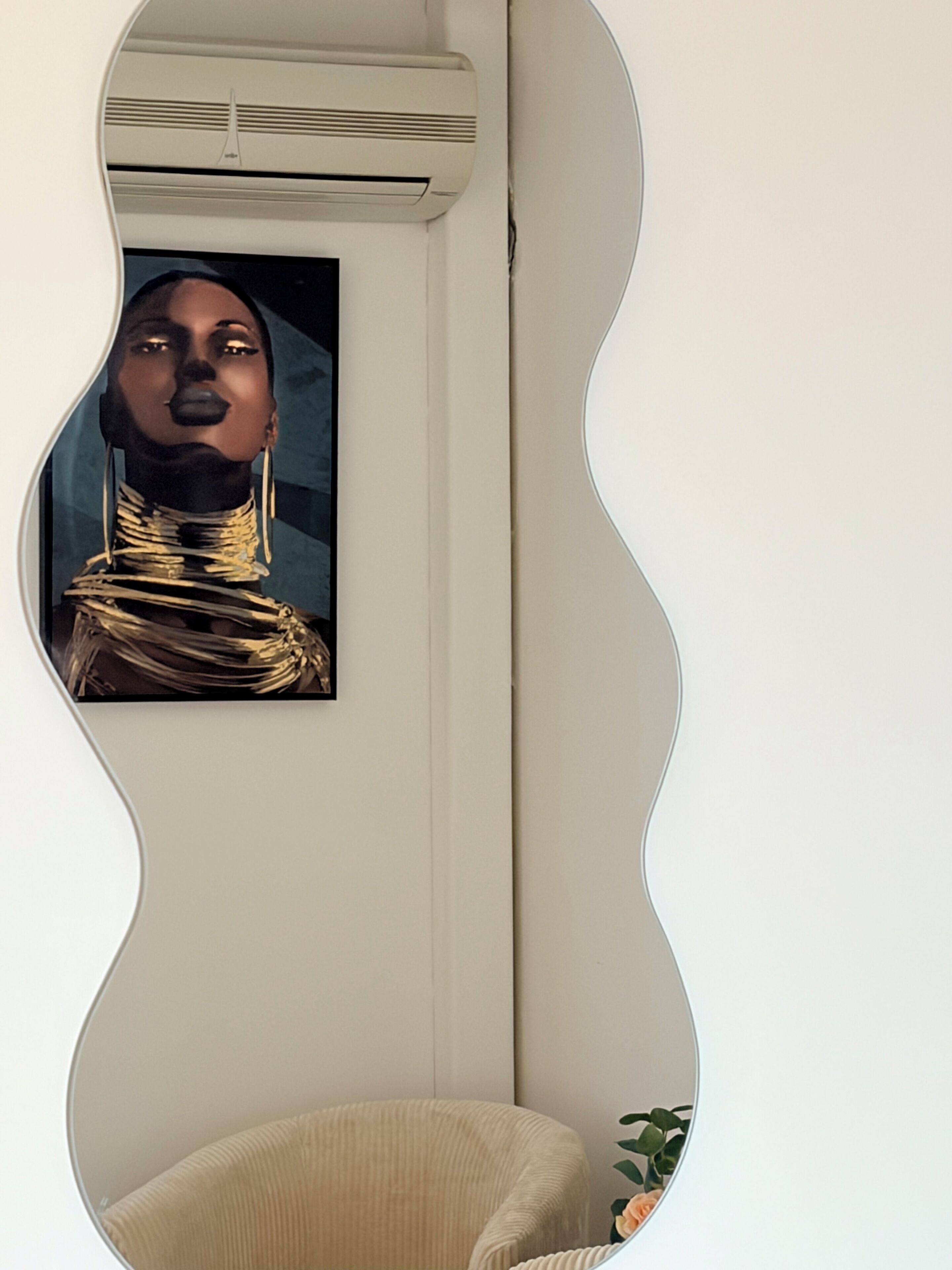 Huoneessa on aaltoileva peili, joka heijastaa taulua, valkoinen tuoli ja ruukussa oleva kasvi.