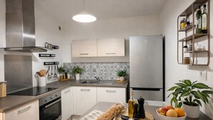 A modern kitchen with stainless steel appliances, a central island with a bread loaf, and a fruit bowl. - Douce parenthèse - T2 Cosy & warm Montélimar station center within walking distance (Montélimar)