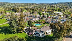 Vue aérienne d’un quartier résidentiel avec des maisons, une piscine et des espaces verts.