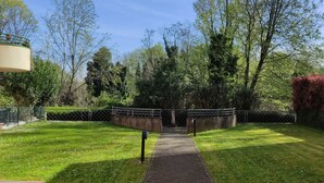 Un cortile con un vialetto che conduce all'ingresso di un edificio, circondato da vegetazione e da una recinzione.