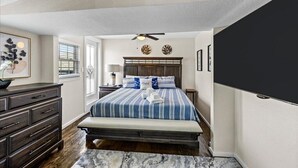 Una camera da letto con un letto, una cassettiera, un comodino e una ventola a soffitto.
