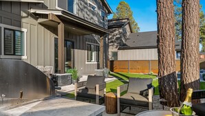 A modern outdoor patio with a stone fireplace, outdoor seating, and a bottle of champagne. - Modern*Fully Fenced Yard*A/C* Near Forest (Flagstaff)