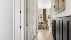 A hallway with white walls, a wooden floor, and a sofa in the background. - Modern*Fully Fenced Yard*A/C* Near Forest (Flagstaff)
