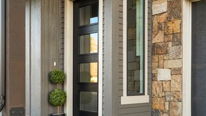A modern house entrance with a black door, stone wall, and a small potted plant. - Modern*Fully Fenced Yard*A/C* Near Forest (Flagstaff)