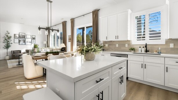 A modern kitchen with white cabinetry, a large island, and a dining area with a sofa and table. - Modern*Fully Fenced Yard*A/C* Near Forest (Flagstaff)