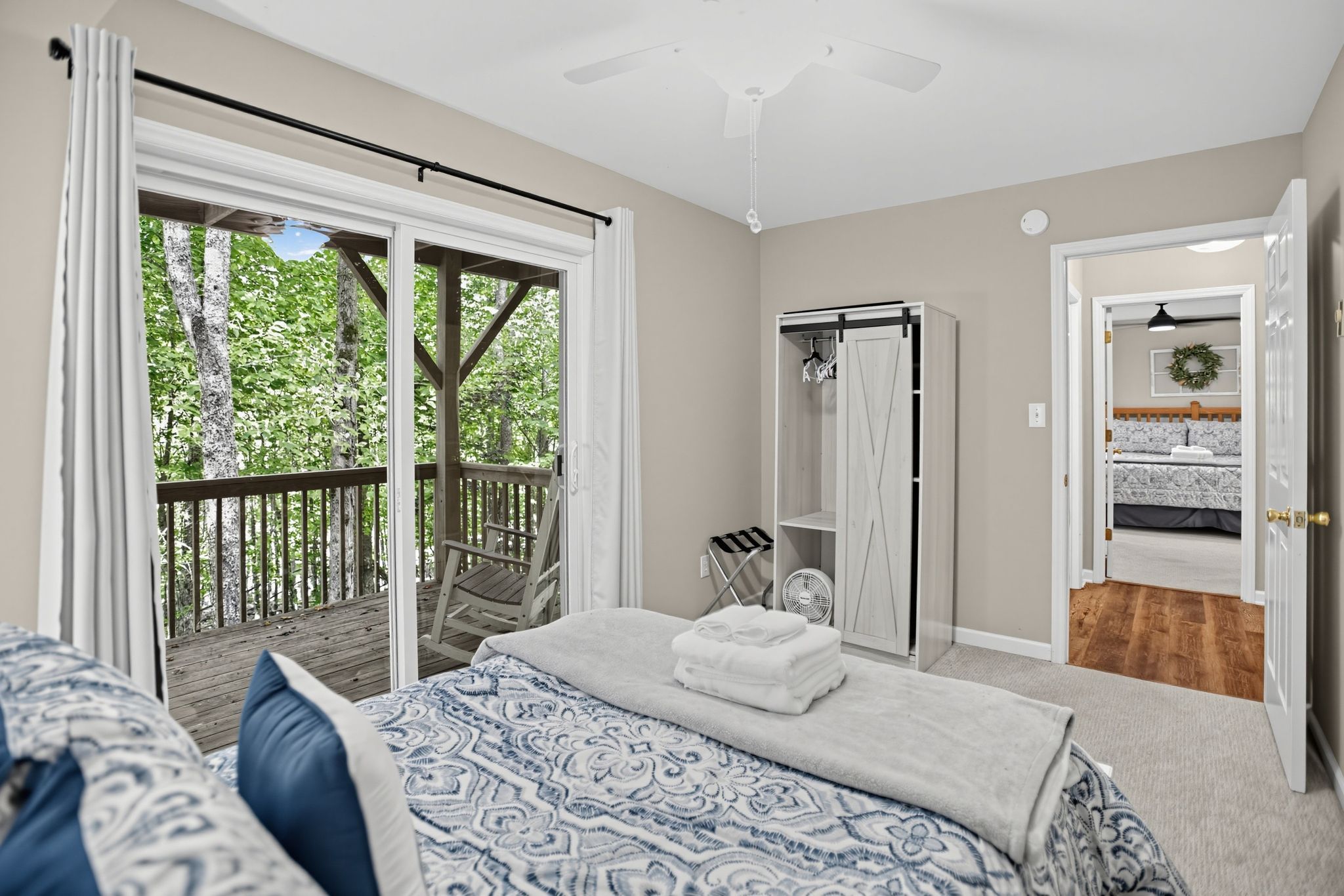 Ein Schlafzimmer mit Bett, Schrank, Balkon und Blick auf Bäume.