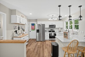 A modern kitchen with white cabinets, stainless steel appliances, and a wooden floor. - Beech Mountain Escape w/ Fireplace & Hot Tub (Beech Mountain)