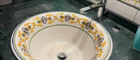 Un baño con un lavabo redondo, un espejo y un grifo.