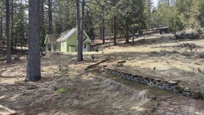 A small cabin with a green roof and a fenced yard, surrounded by pine trees. - 30 Night Minimum, Shasta View Chalet (Weed)