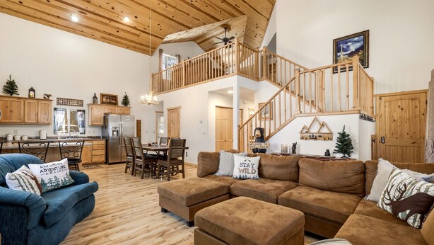 Un vaste espace de vie doté d’un plafond en bois, d’un escalier, d’un coin repas et d’une cuisine.