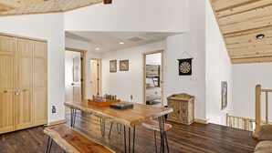 Une pièce spacieuse avec une table en bois, des bancs, un buffet et un jeu de fléchettes.