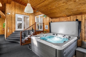 L’intérieur d’un chalet en bois, avec un jacuzzi, un escalier et une vue sur l’extérieur.