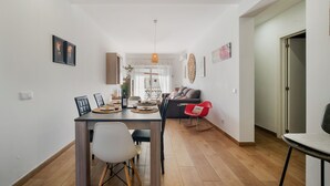 Un soggiorno moderno con zona pranzo, che include un divano, un tavolino da caffè e un tavolo da pranzo con sedie.