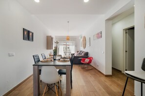 A modern living room with a dining area, featuring a sofa, a coffee table, and a dining table with chairs. - Boat 3 Apt OCV – Steps from beach (100m) and Pool (Albufeira)