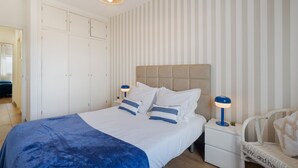 Una camera da letto con un letto, comodini, una sedia e un armadio.