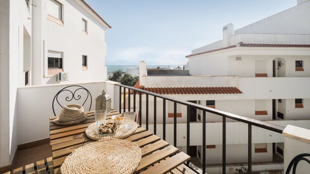 Un balcone con un tavolo di legno, cesti in vimini e una sedia in metallo.