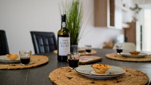 Un tavolo da pranzo imbandito con tovagliette, piatti, bicchieri e una bottiglia di vino.