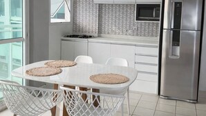 A modern kitchen with white cabinetry, a built-in microwave, and a stainless steel refrigerator. - LUXURY penthouse 6 people seafront pedra do pontal (Rio de Janeiro)