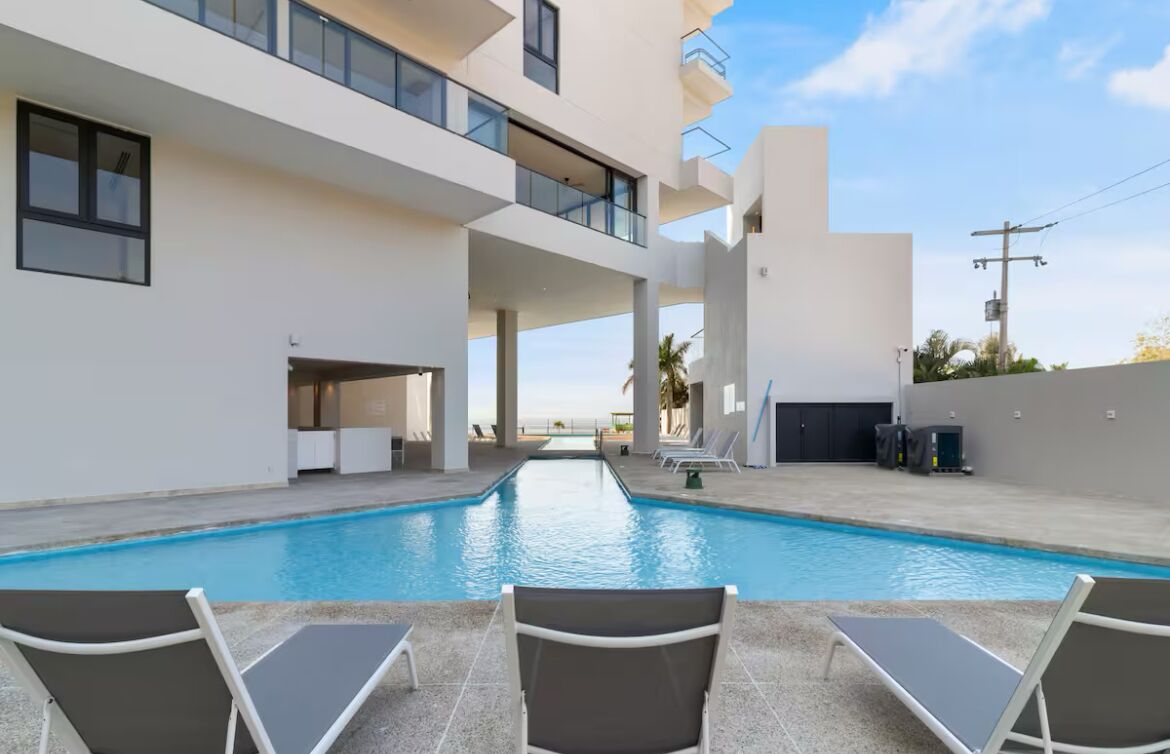 A modern pool area with lounge chairs and a clear view of the sea.