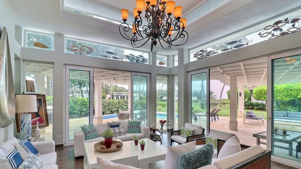 Amplia sala de estar con una gran lámpara de araña, asientos cómodos y ventanas grandes que ofrecen vistas al exterior.