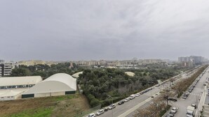 A cityscape with a long road lined with parked cars and a large white building with a curved roof. - Welcome to Bari Sky Terrace (Bari)