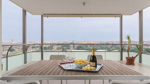 A balcony with a table set for two, featuring a bottle of champagne, a bowl of chips, and glasses. - Welcome to Bari Sky Terrace (Bari)