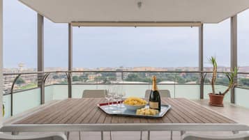 Ein Balkon mit Tisch, gedeckt für zwei Personen, mit einer Champagnerflasche, einer Schüssel Chips und Gläsern.