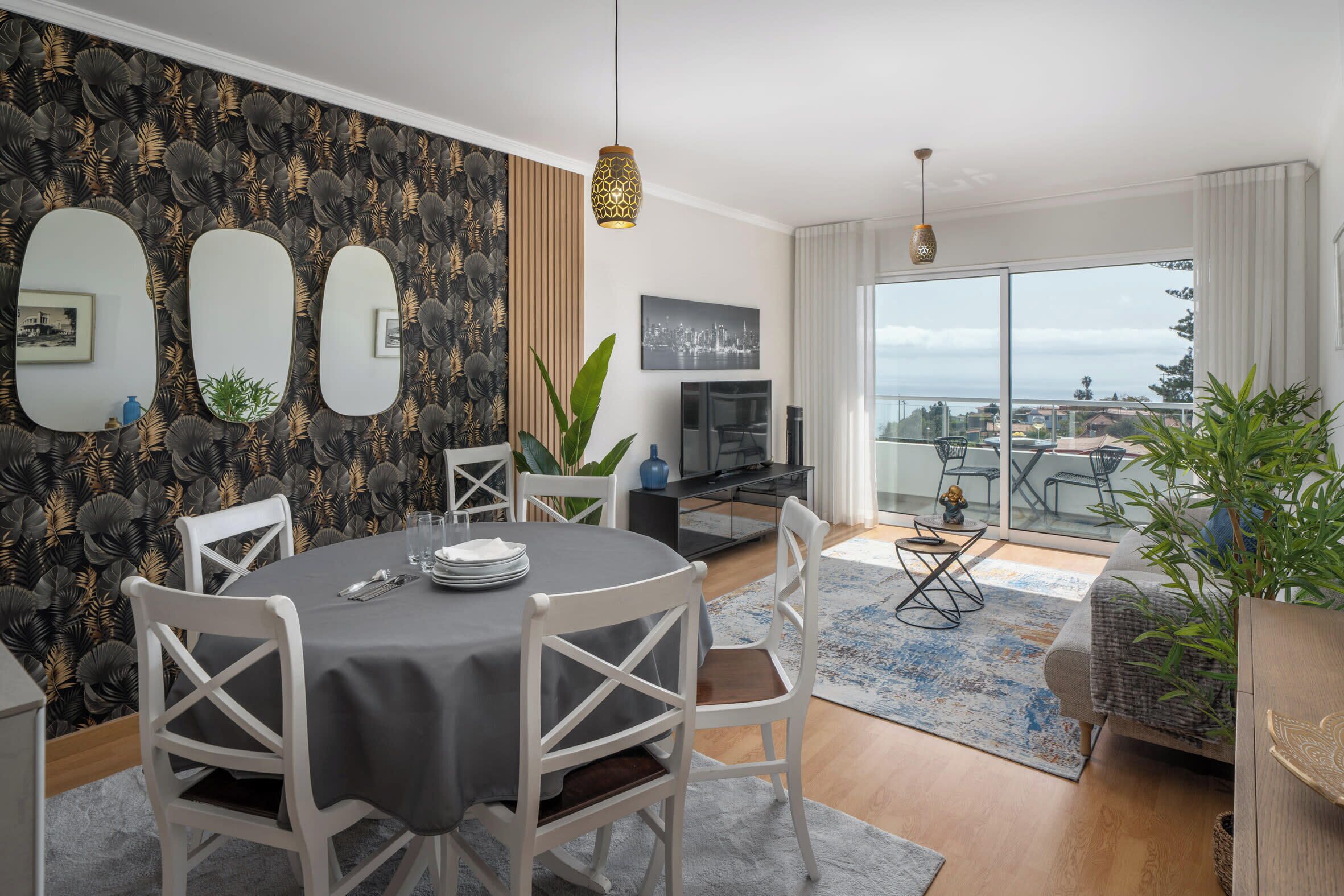 A modern living room with a dining area, large windows, and a city view.