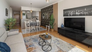 Ein modernes Wohnzimmer mit einer Couch, einem Couchtisch, einem Fernseher und einem Essbereich mit Stühlen und einem Tisch.