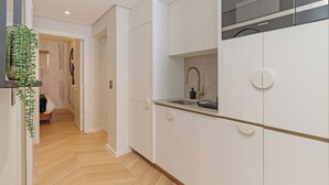 Eine moderne Küche mit weißen Schränken, einem eingebauten Backofen und einer Spüle aus Edelstahl.
