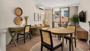 A modern hotel room with a dining area, a sofa, a desk, and a TV mounted on the wall. - Dolce Vita | Lush Sea Point Gem with Balcony (Cape Town)