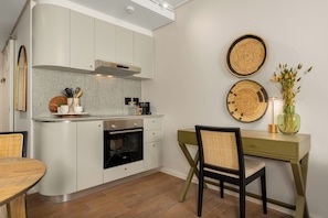 Eine moderne Küche mit weißen Schränken, einem Einbauofen und einem Essbereich mit Holztisch und Stühlen.
