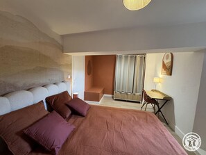 Une chambre avec un grand lit, un bureau et un espace douche.
