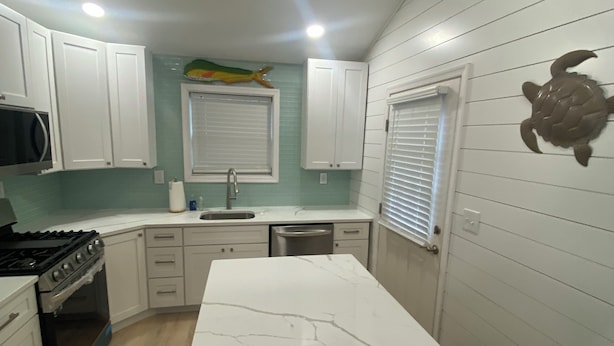 A compact kitchen with white cabinets, a central island, and a microwave. -  Campfire Bliss at the Beach 
Eastern Shore Virginia Cottage Getaway (Horntown)