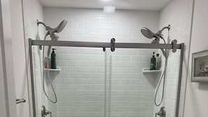 A modern bathroom with a glass-enclosed shower, a toilet, and a sink. -  Campfire Bliss at the Beach 
Eastern Shore Virginia Cottage Getaway (Horntown)